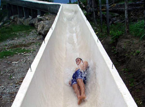 A swimmer zooms down the slide to the pool.